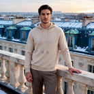 Man wearing beige knit hoodie on balcony overlooking snowy rooftops | Chaps London