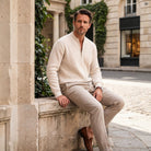Man wearing beige ribbed zip cardigan and trousers, seated on stone ledge outdoors | Chaps London