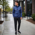 Man wearing navy blue hooded windbreaker jacket with black joggers outdoors | Chaps London