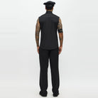 Man wearing black sleeveless shirt, pants, and police cap, rear view | Chaps London