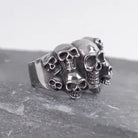 Silver skull ring with multiple cluster skulls, shown on dark stone surface | Chaps London