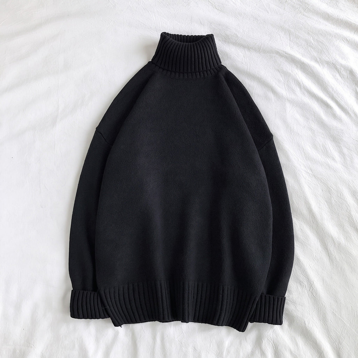Black knit turtleneck sweater with ribbed cuffs, laid flat on fabric | Chaps London