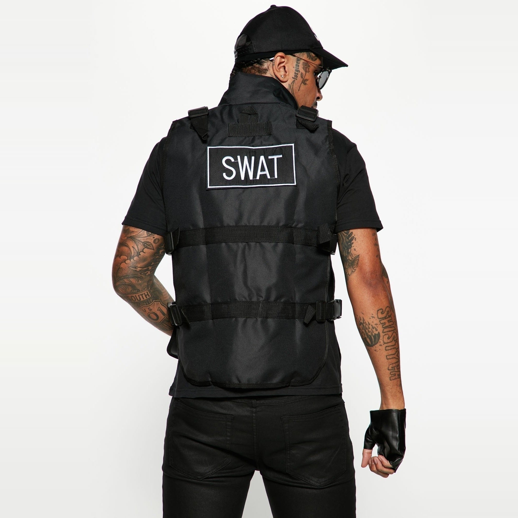 Black SWAT tactical vest worn by man, fingerless gloves, cap, rear view | Chaps London
