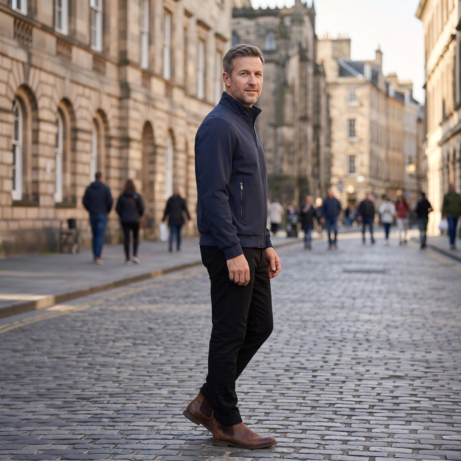 Man wearing navy zip-up jacket and black trousers on cobblestone street | Chaps London