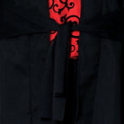 Black jacket with tie closure over red scrollwork patterned fabric, close-up view | Chaps London