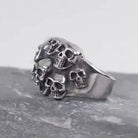 Silver skull-cluster ring on dark rock, flat product shot | Chaps London