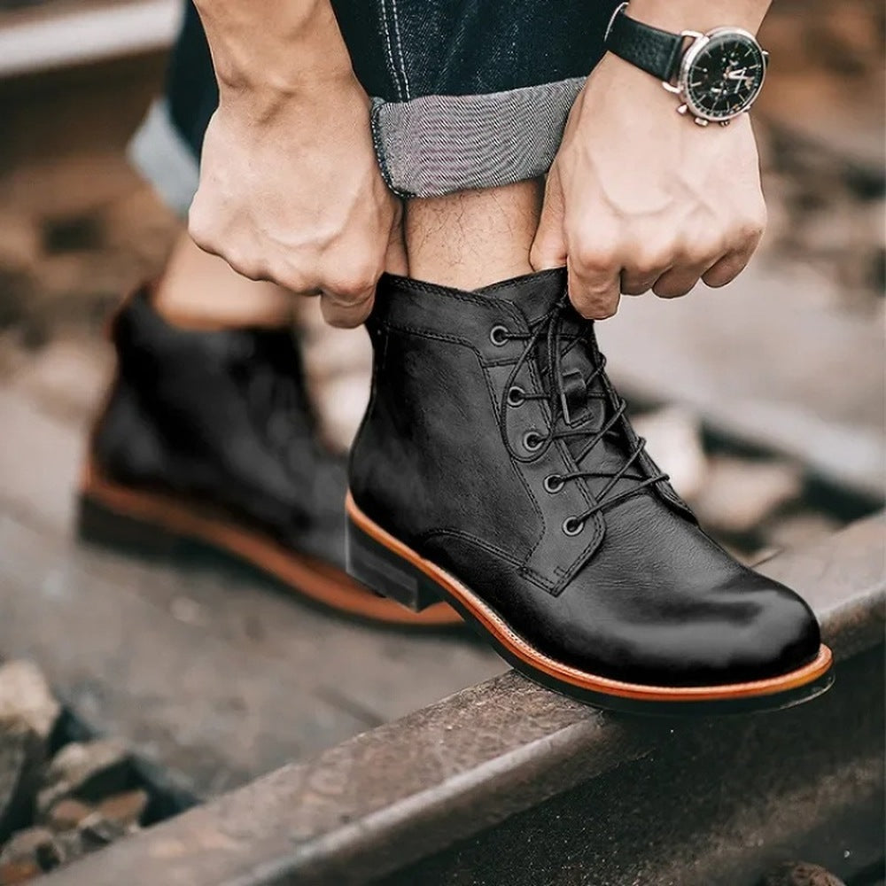 Black lace-up ankle boots worn by person standing on railroad tracks | Chaps London