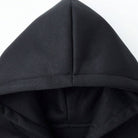 Black hoodie close-up showing pointed hood and drawstring detail, worn by person | Chaps London