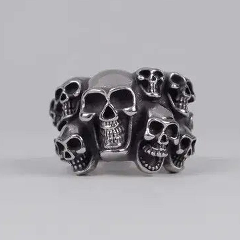 Silver skull ring with multiple faces, shown against plain gray background | Chaps London