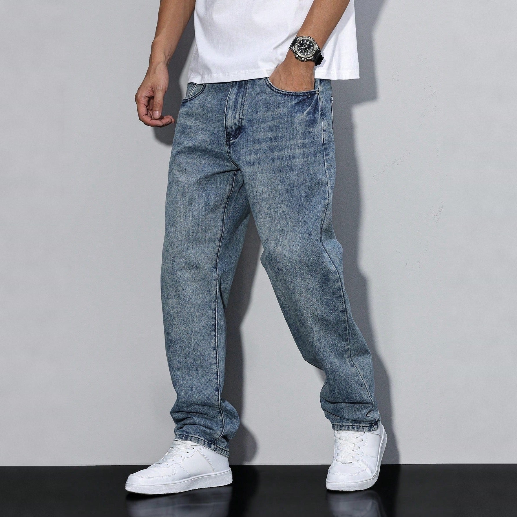 Man wearing washed blue baggy denim jeans with white sneakers, worn look | Chaps London