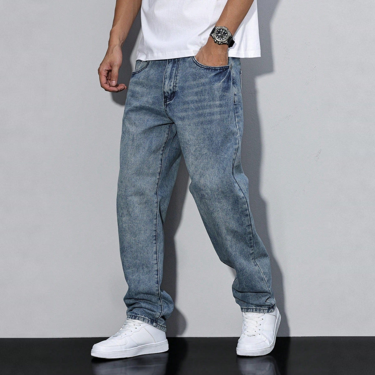 Man wearing washed blue baggy denim jeans with white sneakers, worn look | Chaps London