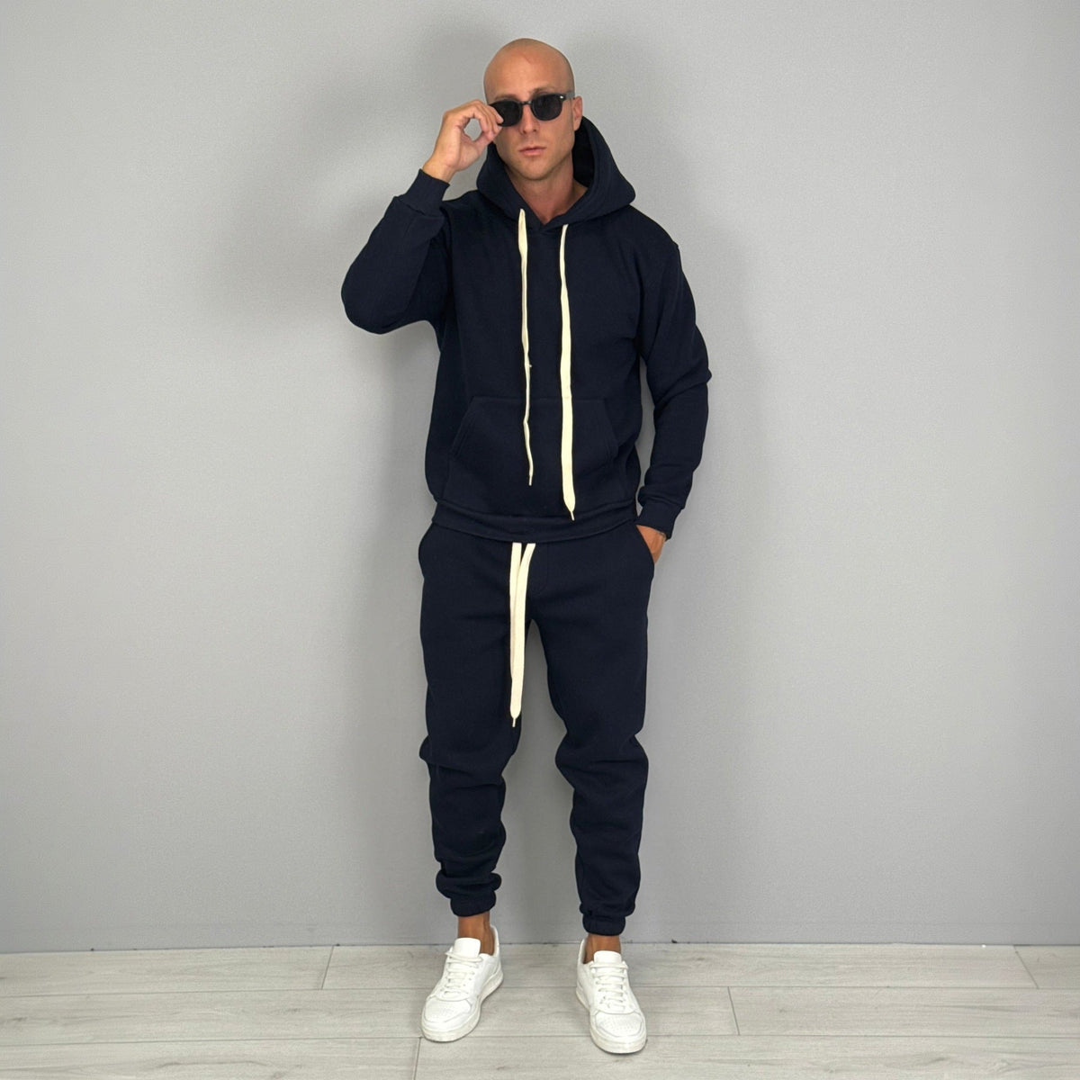 Man wearing navy hoodie tracksuit with matching cuffed joggers and sunglasses | Chaps London