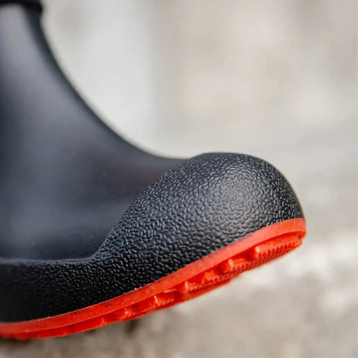 Black ankle welly close-up with textured toe and red ridged sole, worn | Chaps London