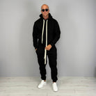 Man wearing black hoodie tracksuit with cuffed joggers and white sneakers | Chaps London