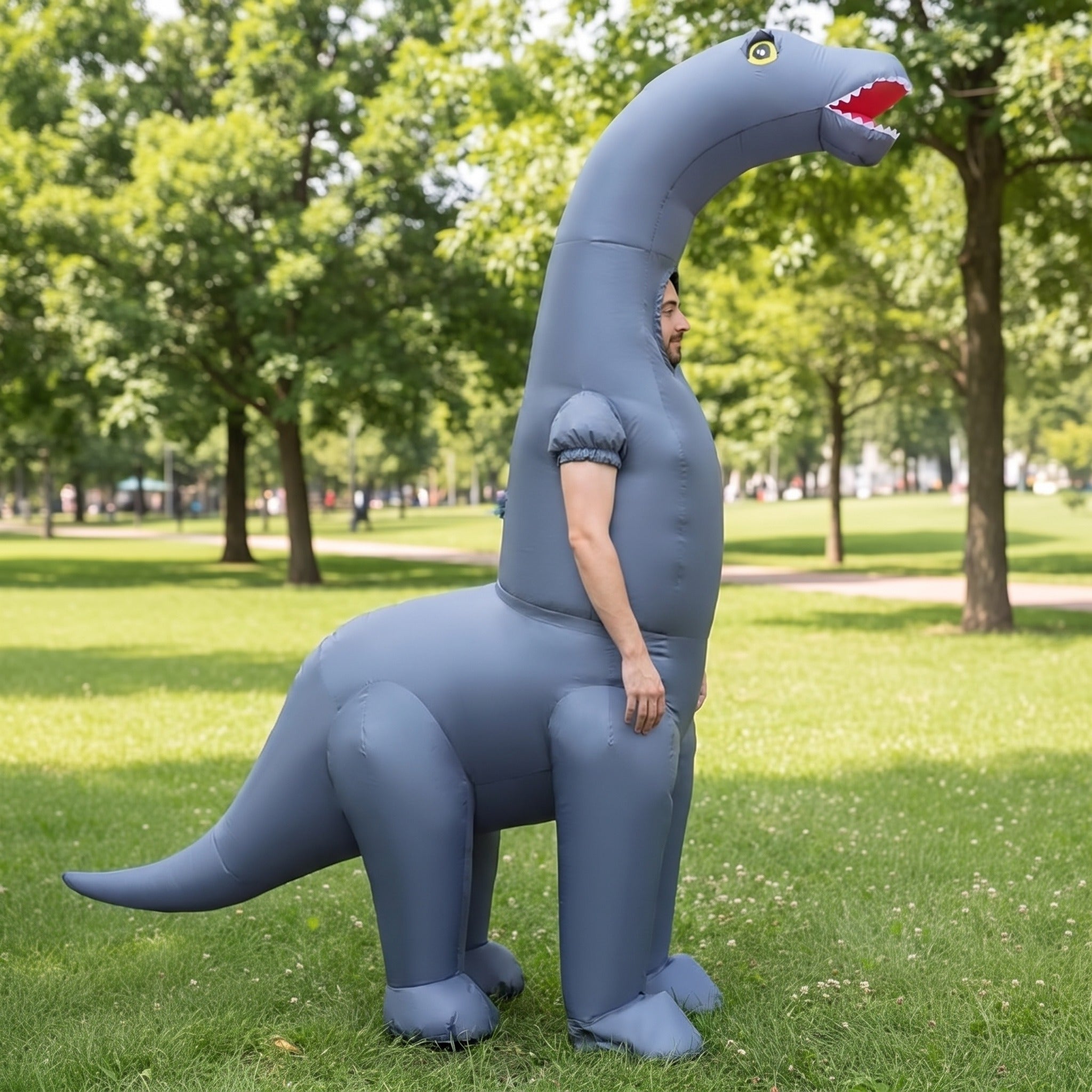 Gray long-neck dinosaur inflatable costume worn by person standing outdoors on grass | Chaps London