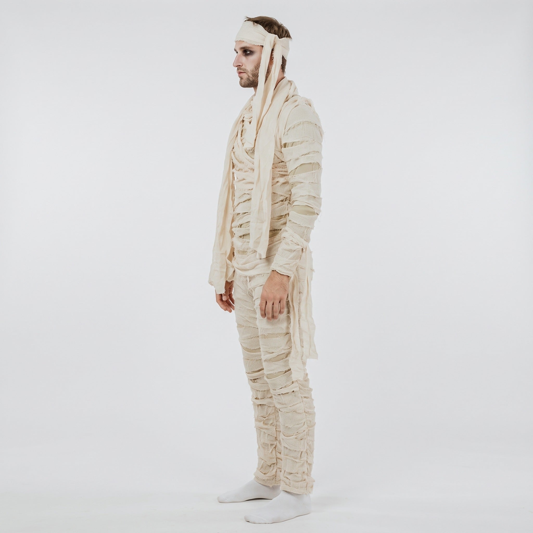 Man wearing cream mummy costume jumpsuit with frayed wraps and headband, side view | Chaps London