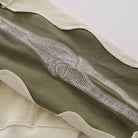 Close-up of olive green sleeve with embroidered skeletal arm design, cream trim | Chaps London