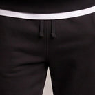 Close-up of black joggers with white waistband and drawstring detail, worn by person | Chaps London