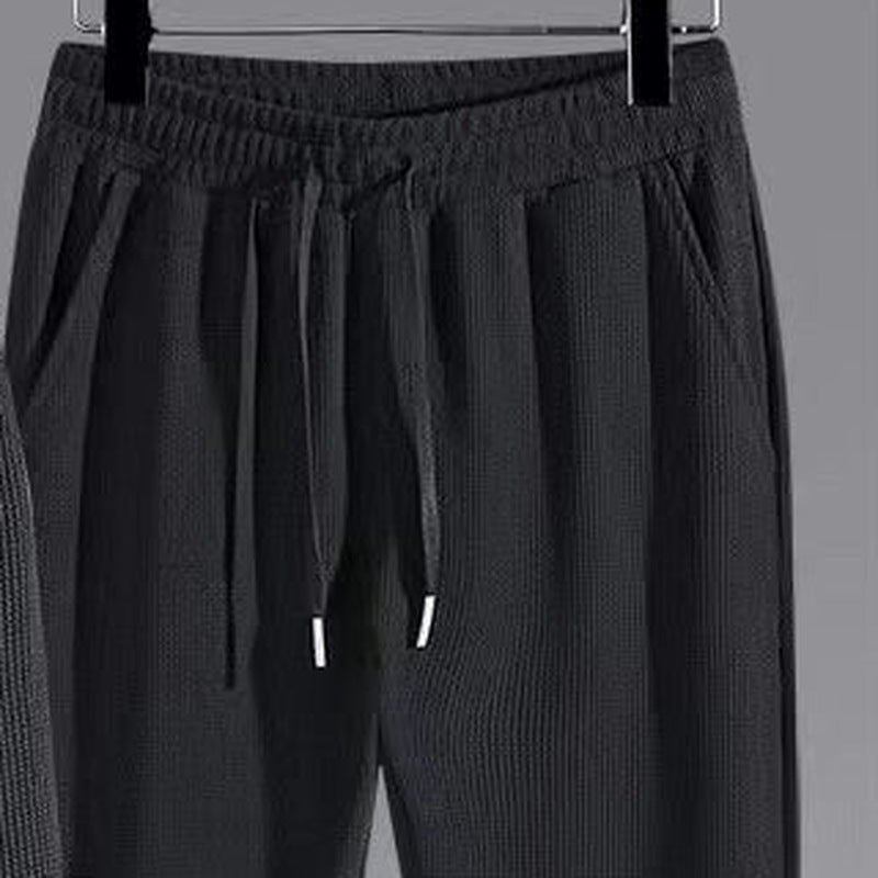 Black waffle-knit joggers on hanger, close-up of drawstring waist and pockets | Chaps London