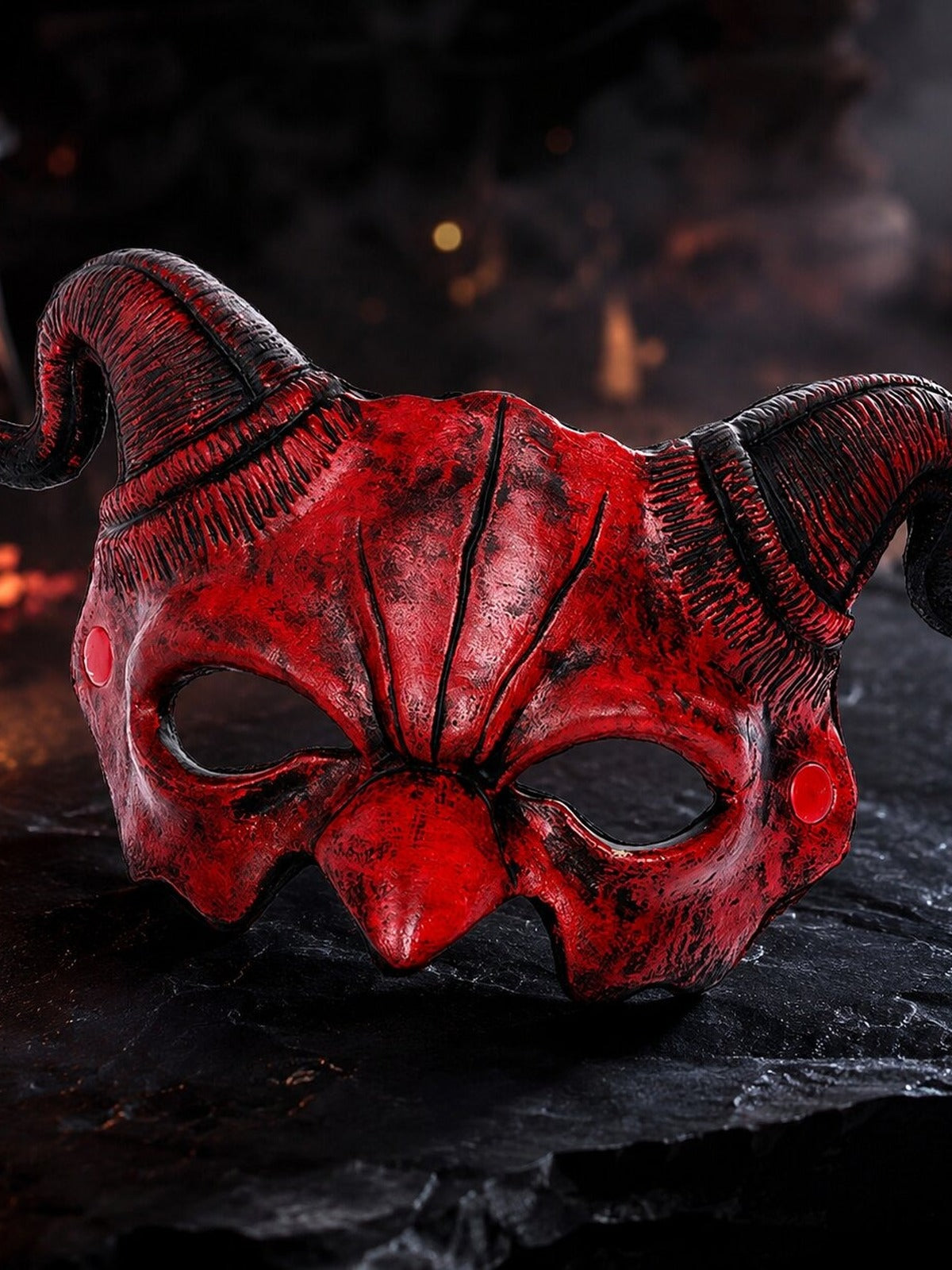 Red demon mask with ram horns on a stone